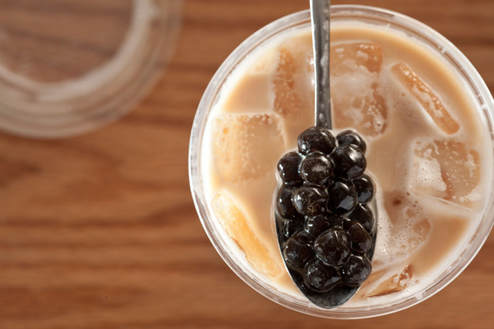 A spoonful of black tapioca pearls over milk tea